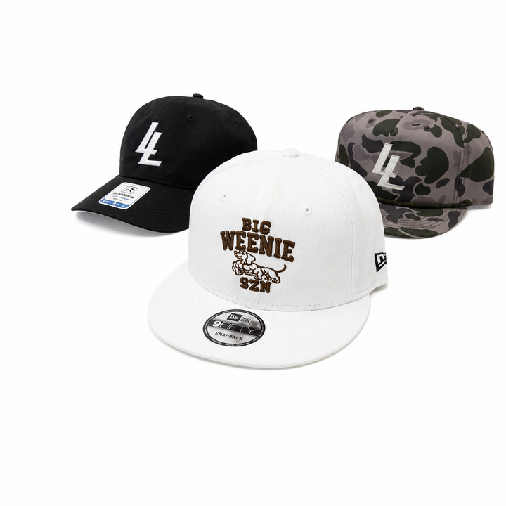 Translation missing: en.Three baseball caps displayed on a white background: a black cap with a white LL logo, a white cap with brown 'BIG WEENIE 52N' embroidery, and a marsh camouflage cap with a cream LL logo. A New Era 9FIFTY sticker is visible on the brim of the white cap