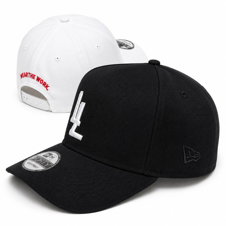 Translation missing: en.Two baseball caps shown on a white studio background: a black cap in front with a white embroidered LL logo on the front and a black New Era logo on the side, plus a black brim sticker; and a white cap behind it with red text reading 'WEAR THE WORK.' on the back