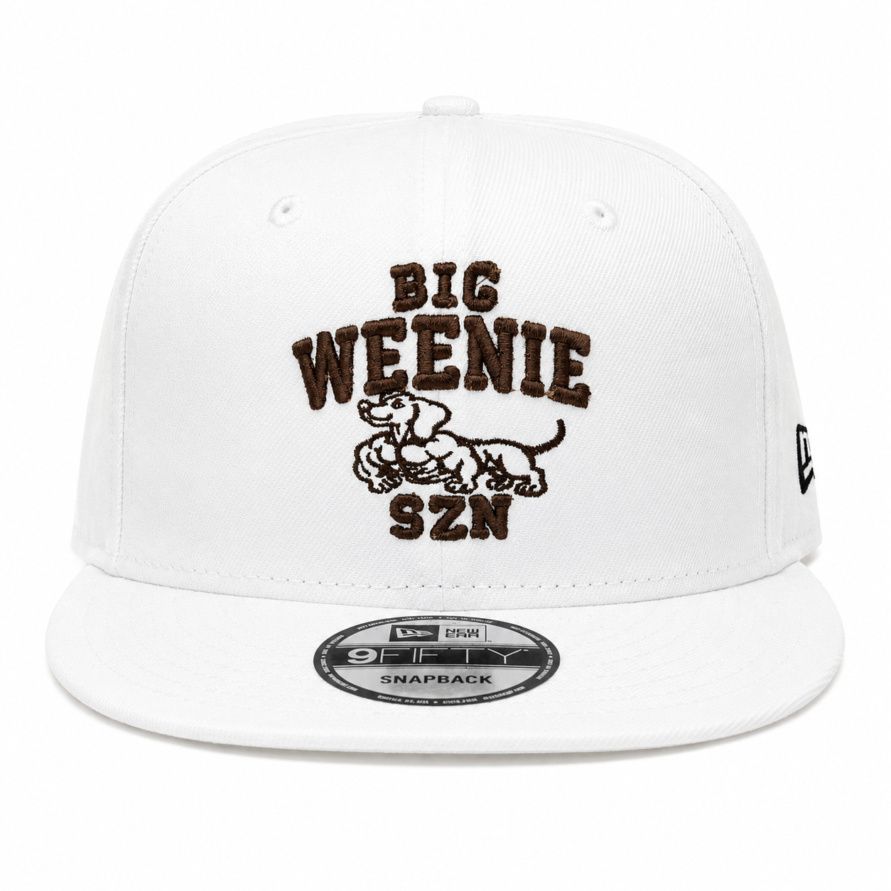 Translation missing: en.A white structured baseball cap with a flat brim, featuring a brown embroidered graphic on the front that reads 'BIG WEENIE SZN' around a swole dachshund. A New Era 9FIFTY sticker is visible on the brim, and a small black New Era flag logo is on the side