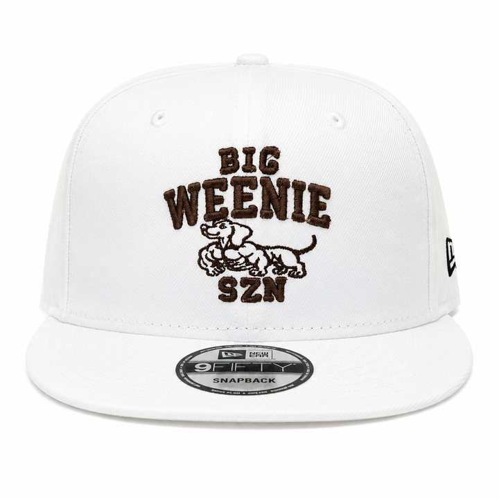 Translation missing: en.A white structured baseball cap with a flat brim, featuring a brown embroidered graphic on the front that reads 'BIG WEENIE SZN' around a swole dachshund. A New Era 9FIFTY sticker is visible on the brim, and a small black New Era flag logo is on the side
