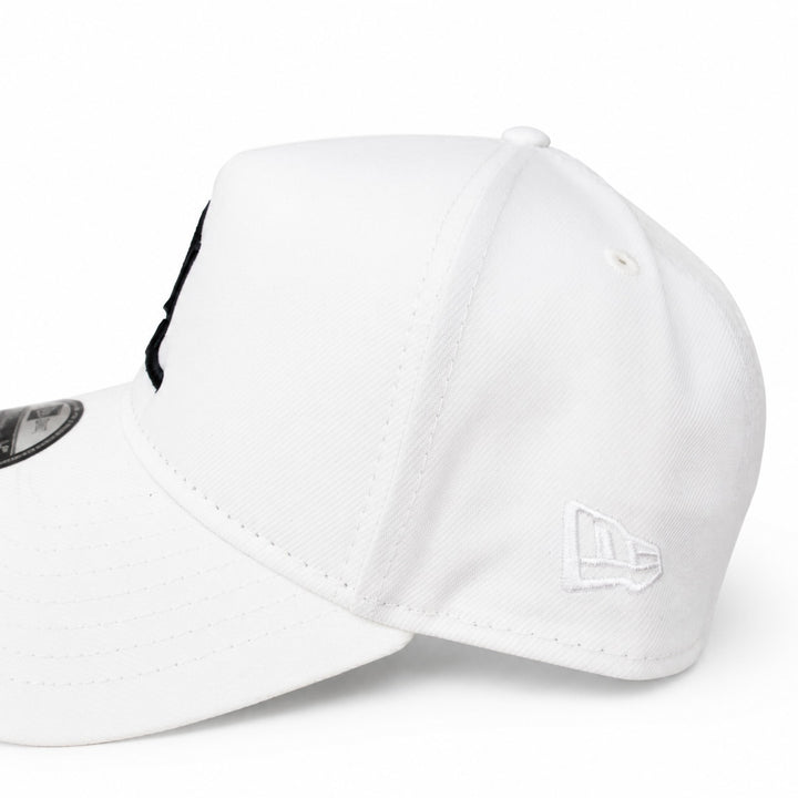 Translation missing: en.A white structured baseball cap shown in a close-up side view on a clean white background. The cap features a white embroidered New Era flag logo on the side and a black embroidered letter on the front panel