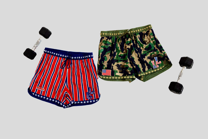 Translation missing: en.Two pairs of shorts, one red and white striped with an American flag logo, the other camouflage, along with two dumbbells on a light gray background