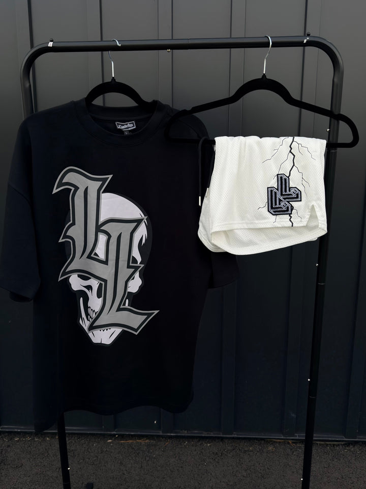 Translation missing: en.Black tee shirt gothic skull and LL logo. White mesh shorts with black lighting strikes folded over hanger. 
