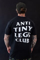 Person wearing a black t-shirt with 'ANTI TINY LEGS CLUB' text on the back against a dark background