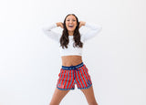 Woman wearing a white crop top and red, white, and blue shorts on a white background