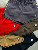 Five color ways of the OG 3” inseam shorts. Obsidian Black, Mocha Tan, Tactical Thigh Green (army dark green), Red Riot (RED), Dark Grey (Gray)
